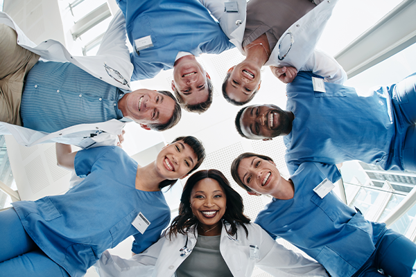 Smiling group of people in scrubs and street clothes.